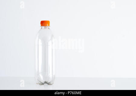 Einzelne leere Wasserflasche gegen hellen weißen Hintergrund isoliert, Orange, Deckel, Kappe Stockfoto