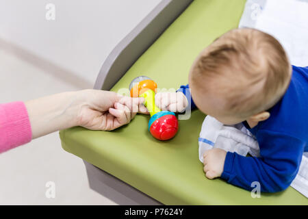 Kind mit Mutter spielt am Wickeltisch. Mom, Spielzeug, baby boy klappern. Ansicht von oben Stockfoto