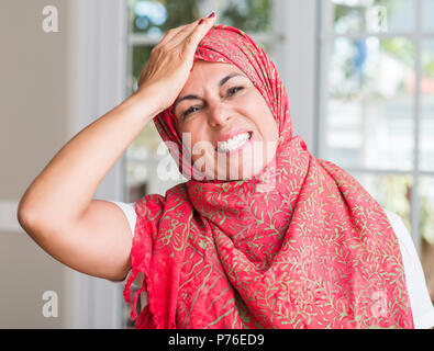 Im mittleren Alter muslimische Frau mit Kopftuch mit Hand betonte am Kopf, mit Scham und Überraschung Gesicht schockiert, wütend und frustriert. Angst und für Nebel umgekippt Stockfoto