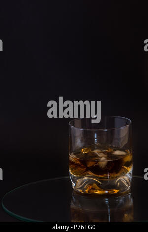 Glas Brandy mit Eis auf dunklem Hintergrund serviert. Stockfoto