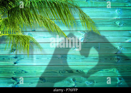 Schatten der Hände bilden ein Herz auf blauem Hintergrund mit Palmen Stockfoto