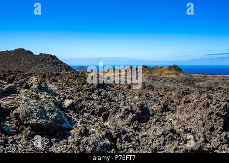 Die große Leere und Einsamkeit der Lanzarote schwarz gefrorener Lava vulkanische Wüste mit dem blauen Wasser des Atlantischen Ozeans im Hintergrund Stockfoto