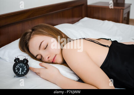 Junge Frau schlafen mit Wecker auf dem Bett am Morgen. Schlafende Mädchen und Radiowecker im Schlafzimmer zu Hause. Schüler oder Schülerin Angst aufwachen Stockfoto