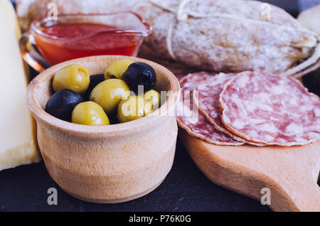 Mediterrane Vorspeisen, Tapas und Antipasti. Verschiedene italienische traditionelle Produkte essen. Leckerer Snack auf Party. Grüne und schwarze Oliven mit sa Stockfoto