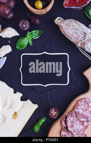 Tabelle mit mediterranen Vorspeisen, Tapas und Antipasti. Verschiedene Bankett Essen im italienischen Stil eingerichtet. Leckerer Snack auf Party. Leere Schiefertafel für Yo Stockfoto