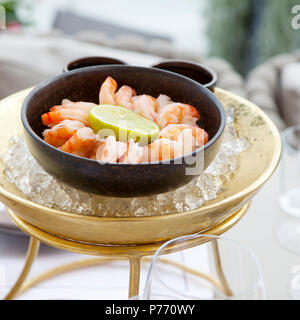 Garnelen mit Kalk in eine gusseiserne Schale in das Eis auf einem Tisch in einem Restaurant Stockfoto
