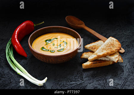 Pikante Kürbis creme Suppe in einem Ton Platte auf einem dunklen Hintergrund. Stockfoto