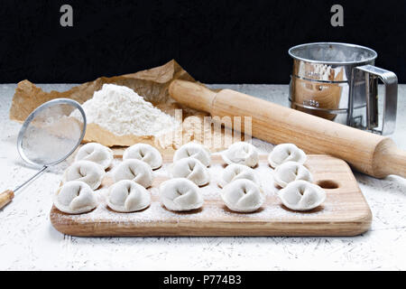 Der Prozess der Home - Knödel gemacht. Raw hausgemachte Knödel auf einem Holzbrett. Knödel formen. Stockfoto