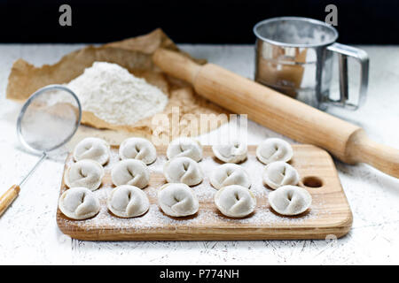 Der Prozess der Home - Knödel gemacht. Raw hausgemachte Knödel auf einem Holzbrett. Knödel formen. Stockfoto