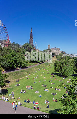 Die Menschen genießen die Sonne im Osten die Princes Street Gardens mit dem Scott Monument und der Balmoral Hotel Edinburgh Schottland Großbritannien Stockfoto