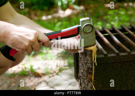 Person Hockend mit Brennholz splitting Kleinholz zu machen Stockfoto