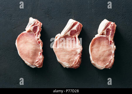 Ein Stück frisches Schweinefleisch auf dunklem Stein, Ansicht von oben Stockfoto