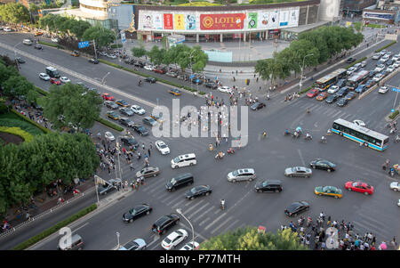 Gruppe von Menschen Überqueren einer verkehrsreichen Straße mit Autos und Fahrräder in der Stadt Beijing in China Stockfoto