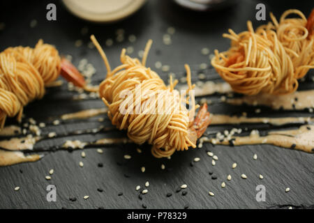 Nahaufnahme Nahrung Foto von gebratenen Riesengarnelen in ei Nudeln auf schwarzem Schiefer Hintergrund. Asiatische Kultur und Küche. Essen Bild von Garnelen für Design von Caf Stockfoto
