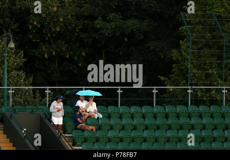 Zuschauer Unterschlupf vor dem Regen auf Gericht zwei während einer Regenunterbrechung an Tag drei der Wimbledon Championships in der All England Lawn Tennis und Croquet Club, Wimbledon. Stockfoto