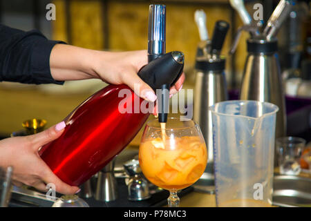 Frau Barkeeper gießt aus einem Cocktail in ein Glas, das Hintergrundbild Stockfoto