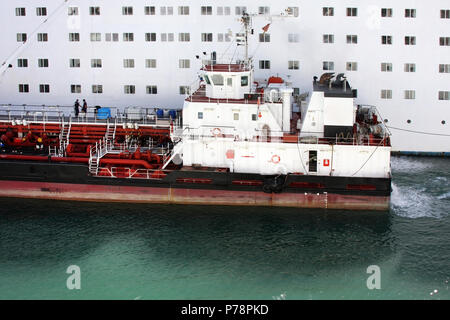 Bereitstellung von Schiff tanken grossen weissen Passagier Kreuzfahrtschiff. Betankung von schweren Nutzfahrzeugen Schiff im Wasser am Hafen. Stockfoto