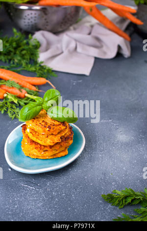 Pfannkuchen aus Karotte und Basilikum, gesunden Lebensmitteln aus Gemüse. Grauer Hintergrund, helle Gemüse. Platz kopieren Stockfoto