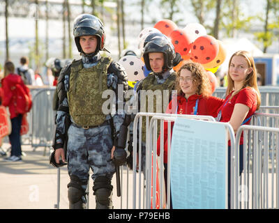 Sankt Petersburg. Russland - 03. Juli 2018. Schwere ausgestattete Polizei wachen und Freiwilliger am Eingang in FIFA WM Schweden - Schweiz auf Krest Stockfoto