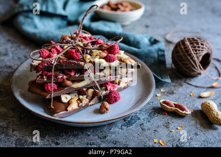 Hausgemachte Schokolade Rinde mit Haselnüssen, Erdnüsse, Preiselbeeren und Gefriergetrockneten Himbeeren Stockfoto