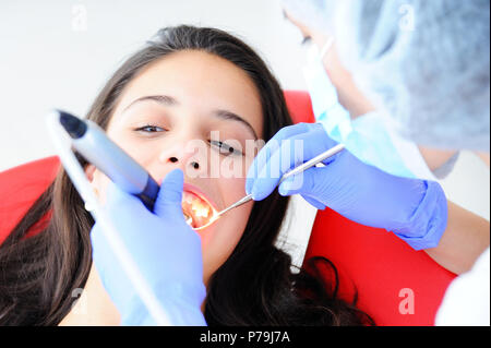 Junge schöne Mädchen in der Zahnarztpraxis. Kinder Zahnarzt untersucht die Zähne zu einem Kind. Stockfoto