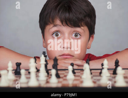 Kleiner Junge spielt Schach auf grauem Hintergrund Stockfoto