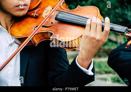 Kunst und Künstler. Junge eleganten Mann Geiger spielen Geige auf Schwarz. Klassische Musik. kleiner Junge Musikinstrument. Stockfoto