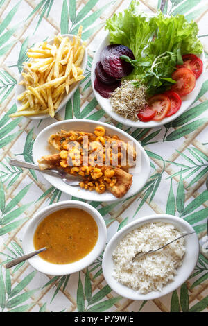 Florianopolis, Santa Catarina, Brasilien. Gerichte der typischen Strand Essen: gebratene Garnelen, Reis, Salat, Pommes und Fischeintopf auf einem rustikalen Tisch serviert mit Whi Stockfoto