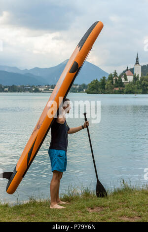 Junger Mann mit paddle Board auf dem See Stockfoto