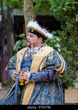 Maryland Renaissance Festival Schauspieler porträtiert König Henry VIII ruht im Freien, bei einem Drink in seinem bejeweled Hände. Er schaut in die Ferne. Stockfoto