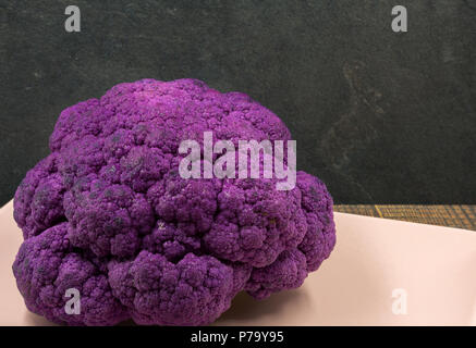 Nahaufnahme eines lila Blumenkohl auf einem hellen Rosa Gericht angeordnet. Horizontale Ansicht. Stockfoto