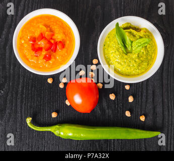 Sortierte Hummus mit Gemüse auf einem schwarzen Holz- Hintergrund Stockfoto