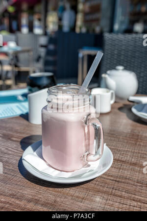 Erdbeer Milchshake Trinken in einem großen ungewöhnlichen Glas mit Griff Stockfoto