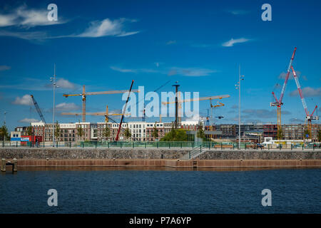 Eine wir-Krieg von hohen Kräne Aufstieg über eine neue Wohnanlage in den alten Hafen von Amsterdam. Stockfoto