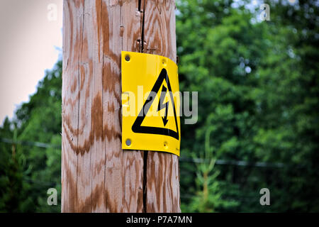 Elektrische Zeichen auf einem hölzernen Pfosten mit verschwommenen Hintergrund. Stockfoto