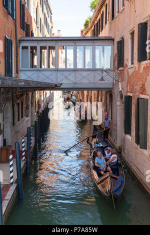 Gondeln mit Touristen in Rio del Vin, Castello, Venedig, Venetien, Italien vorbei unter die überdachte Fußgängerbrücke zwischen den Gebäuden der Danieli H Stockfoto