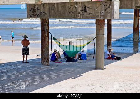 Eine Gruppe von Strand goers hängen unter einem betonpfeiler an den Ufern des St. Augustine Beach, Florida USA Stockfoto