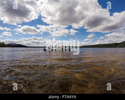 Aviemore am 4. Juli 2018. Sengende Sonne am Loch Morlich in Cairngorm National Park. Zwei Mädchen und ihre Schlittenhunde Genießen der ungewöhnlich warme Wetter in einem kanadischen Kanu. Kredit Alan Oliver/Alamy leben Nachrichten Stockfoto