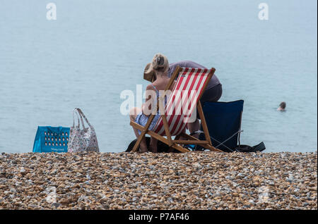 Lyme Regis, Dorset, Großbritannien. 5. Juli 2018. UK Wetter: Sonnig in Lyme Regis. Ein paar sitzen auf den Liegestühlen am Strand von der Küstenstadt Lyme Regis. Credit: PQ/Alamy leben Nachrichten Stockfoto