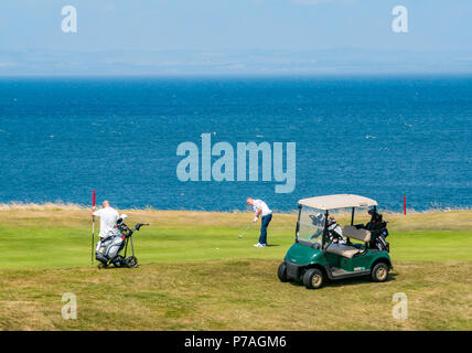 North Berwick, East Lothian, Schottland, Vereinigtes Königreich, 5. Juli 2018. Golfspieler mit einem Golfbuggy spielen auf Glen Golf neben dem Firth von weiter Stockfoto