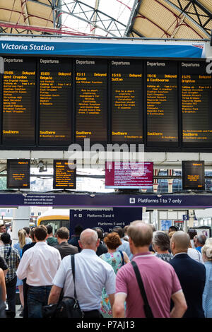 London, Großbritannien. 5. Juli 2018. Fahrgäste warten Züge am Bahnhof Victoria vor einem Board zeigt Züge verzögert nach einem Problem mit Signalanlagen in Streatham im Südosten von London, die gestern Abend entdeckt wurde. Nach Angaben von Network Rail zahlen, Victoria ist Großbritanniens zweite verkehrsreichsten Bahnhof mit 75,8 Mio. Pkw- und Ausfahrten im Jahr. Dienstleistungen auf der Gatwick Express, Thameslink und Südlichen Züge haben durch die Signalisierung Problem betroffen zu sein, mit vielen Annullierungen und Verspätungen. Credit: Mark Kerrison/Alamy leben Nachrichten Stockfoto