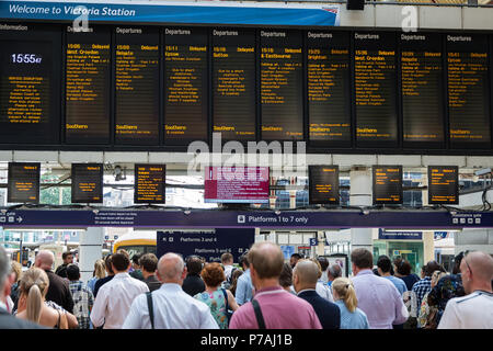 London, Großbritannien. 5. Juli 2018. Fahrgäste warten Züge am Bahnhof Victoria vor einem Board zeigt Züge verzögert nach einem Problem mit Signalanlagen in Streatham im Südosten von London, die gestern Abend entdeckt wurde. Nach Angaben von Network Rail zahlen, Victoria ist Großbritanniens zweite verkehrsreichsten Bahnhof mit 75,8 Mio. Pkw- und Ausfahrten im Jahr. Dienstleistungen auf der Gatwick Express, Thameslink und Südlichen Züge haben durch die Signalisierung Problem betroffen zu sein, mit vielen Annullierungen und Verspätungen. Credit: Mark Kerrison/Alamy leben Nachrichten Stockfoto