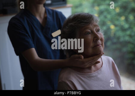 Physiotherapeuten mit einer Nackenmassage zu den älteren Frau Stockfoto