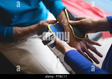 Physiotherapeuten setzen auf eine Handgelenkstütze auf älterer Frau Klammer Stockfoto