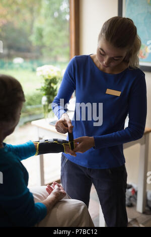 Physiotherapeuten setzen auf eine Handgelenkstütze auf älterer Frau Klammer Stockfoto