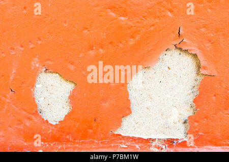 Teil einer Mauer aus Stein mit orange abblätternde Farbe Stockfoto