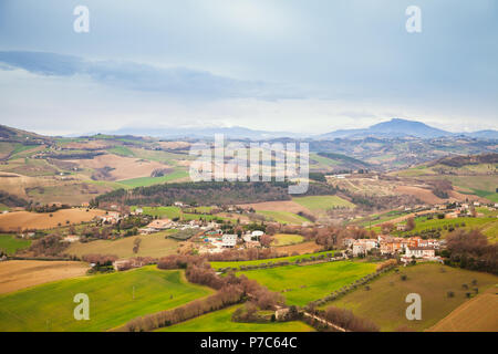 Ländliche Panorama der italienischen Landschaft im Frühling. Provinz Fermo, Italien. Dörfer und Felder auf Hügeln unter blauen bewölkten Himmel Stockfoto