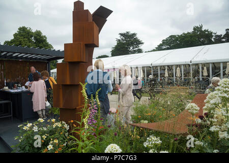 Leute stehen, Reden durch Anzeige der großen ursprünglichen Garten metall Skulpturen auf den Handel stand-RHS Chatsworth Flower Show, Derbyshire, England, Großbritannien Stockfoto
