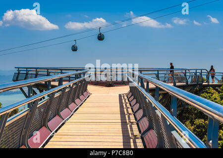 Ein Spaziergang auf der Langkawi Sky Bridge in Richtung der dreieckigen Aussichtsplattform am Ende aus der Sicht eines Touristen. Ein blauer Himmel, weiße Wolken und Hängen Stockfoto