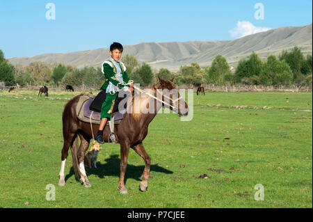 Kasachischen Jungen in traditioneller Kleidung auf einem Pferd, Sati Dorf, Tien Shan Gebirge, Kasachstan Stockfoto